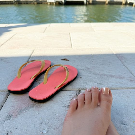 Fresh nude pedicure next to coral flip-flops on a Cape Coral dock