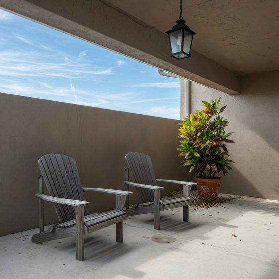 Two grey Adirondack chairs on a taupe porch