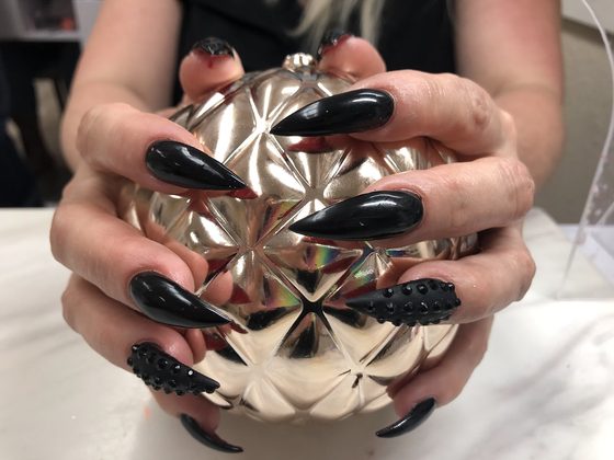 Long black stiletto nails with studs, done at Envy Salon